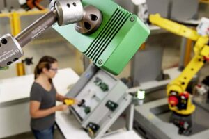 A technician working alongside industrial robots on a production line